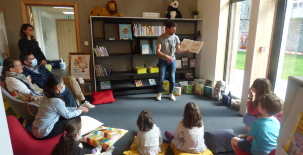 Simon, de la librairie M'Lire, en plein lecture animée devant des enfants assis sur des coussins