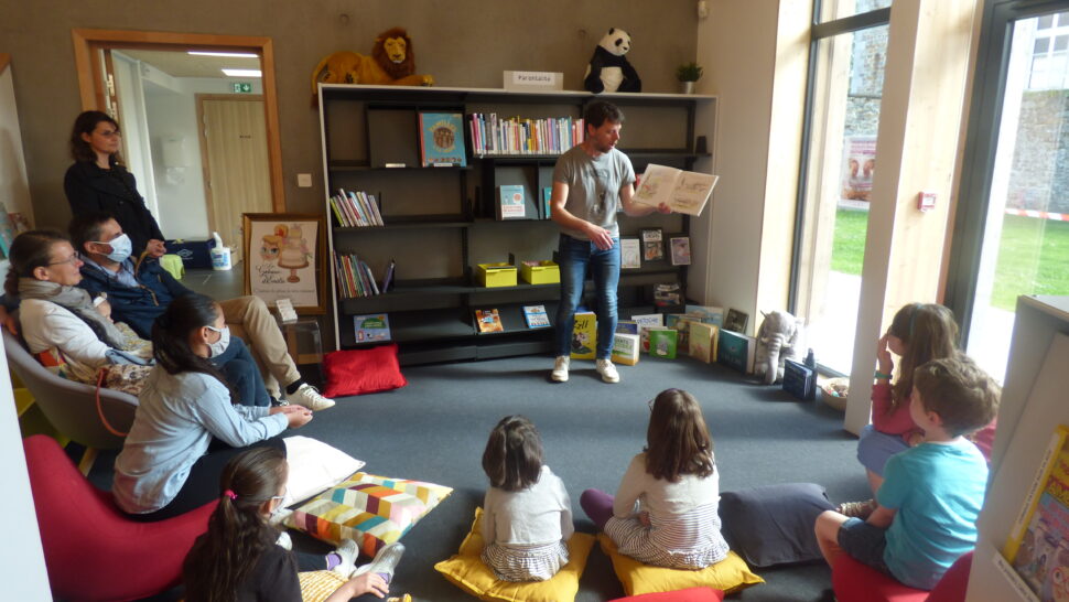 Simon, de la librairie M'Lire, en plein lecture animée devant des enfants assis sur des coussins