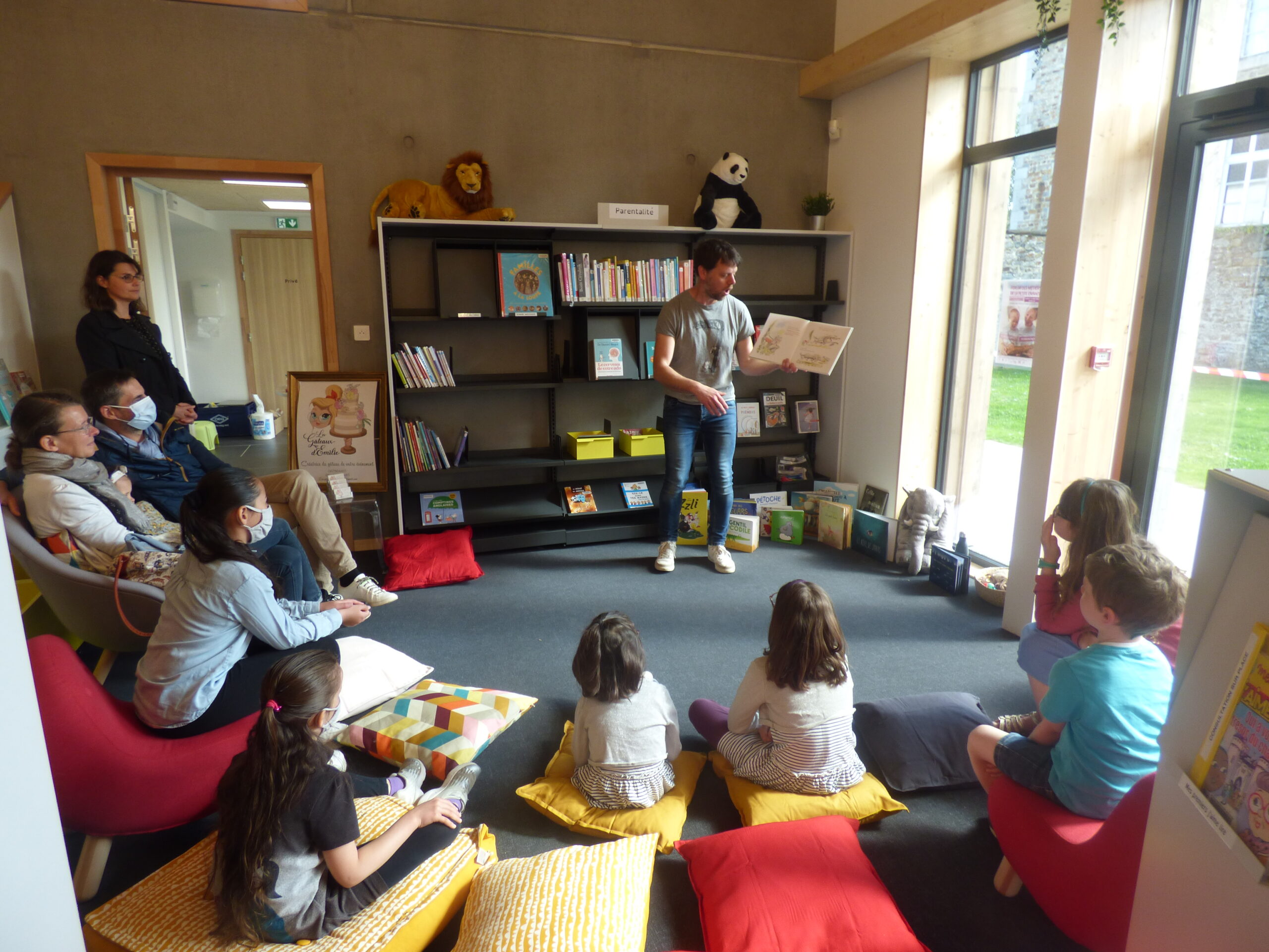 Simon, de la librairie M'Lire, en plein lecture animée devant des enfants assis sur des coussins